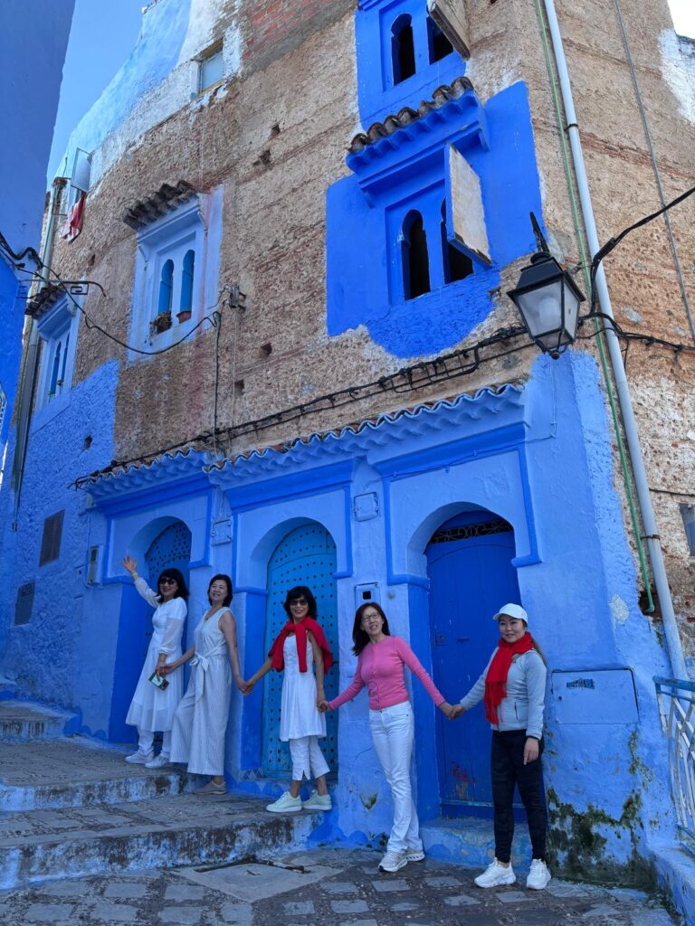 Traditional blue-painted house in Chefchaouen with visitors enjoying the scenic streets.