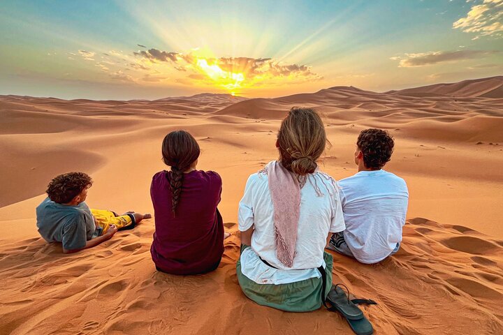 People watching the sunrise over the golden dunes of Erg Chebbi, Sahara Desert, Morocco