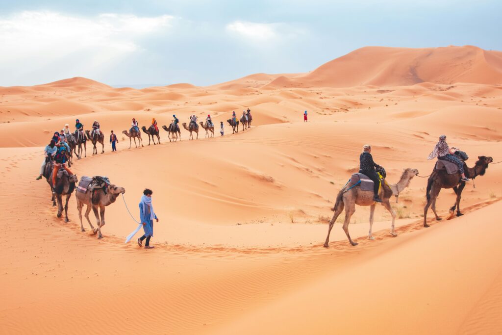 Camel trekking tour in the Sahara Desert near Merzouga with travelers riding camels across the Erg Chebbi dunes