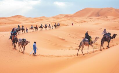 Camel trekking tour in the Sahara Desert near Merzouga with travelers riding camels across the Erg Chebbi dunes