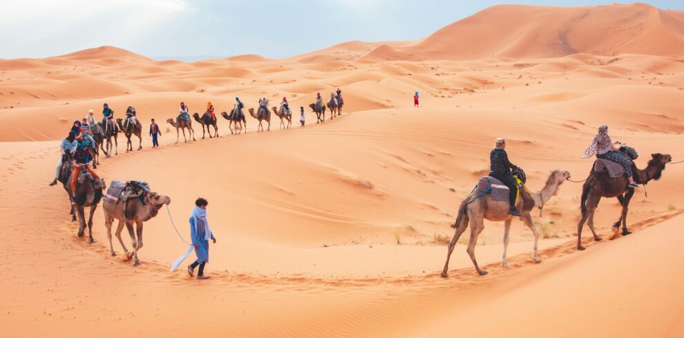 Camel trekking tour in the Sahara Desert near Merzouga with travelers riding camels across the Erg Chebbi dunes